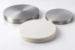 Concept render of two metal sputtering target discs and one ceramic disc on a white surface